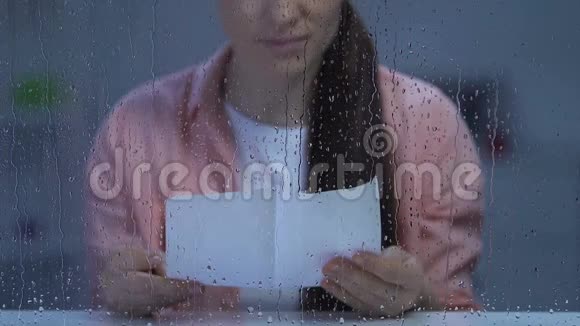 坐在雨窗后面读信的孤独的女士心烦意乱思念家人视频的预览图