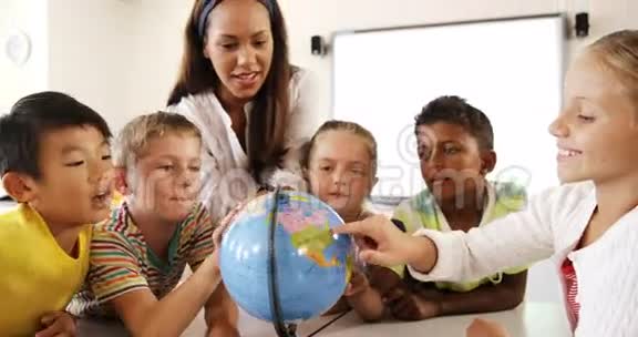 教师协助学生在课堂上阅读地球仪视频的预览图