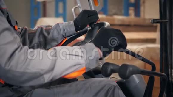 关闭方向盘和杠杆一个人驾驶叉车穿过工厂的仓库穿制服的司机视频的预览图