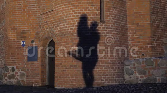 影子里一对夫妇在石墙上积极跳舞的剪影视频的预览图