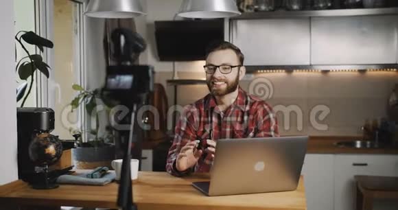 快乐年轻成功的高加索职业博客男子微笑为vlog制作视频使用相机在家里慢动作视频的预览图