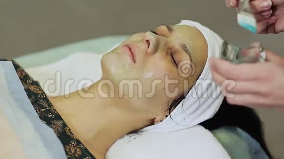 为在美容院戴化妆品面膜的年轻女性提供水疗疗法把巧克力面膜敷在女孩脸上视频的预览图