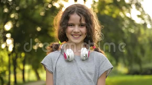 漂亮的棕色眼睛带耳机的白人小女孩的肖像快乐的微笑儿童视频的预览图