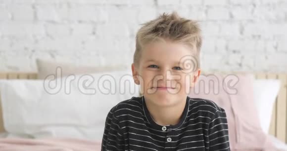 五岁的小男孩微笑着看着坐在他房间里的照相机的画像视频的预览图