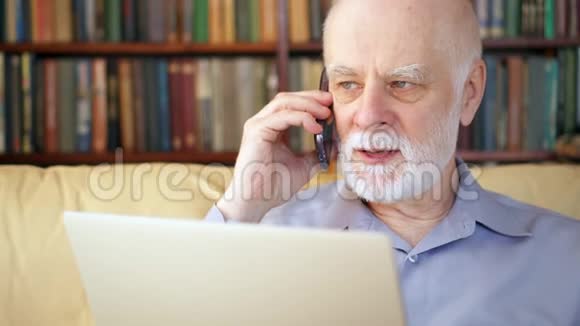 老人坐在家里手提电脑和智能手机在屏幕上用手机讨论项目视频的预览图