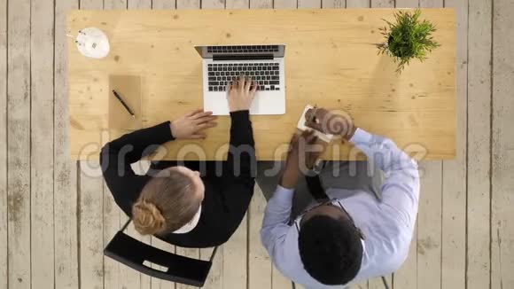 两个企业家坐在一起在办公桌上工作把笔记记在笔记本上视频的预览图