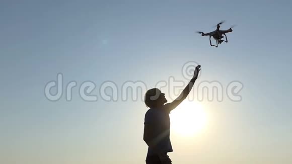 年轻男子试图触摸一架飞行无人机在日落时在斯洛文尼亚视频的预览图