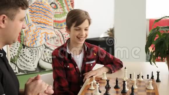 快乐的十几岁的孩子笑着赢得了他的父亲的国际象棋视野慢动作视频的预览图