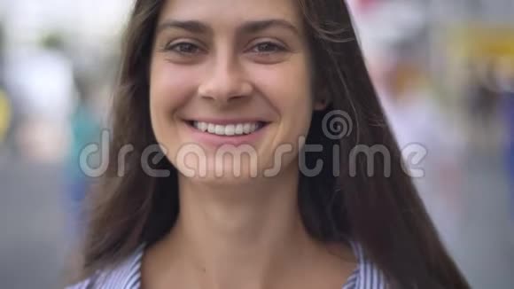 快乐美丽的女人带着牙齿微笑看着相机站在城市的街道上户外视频的预览图