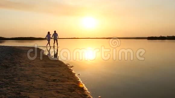 日落时分一对年轻的幸福夫妇奔向大海视频的预览图