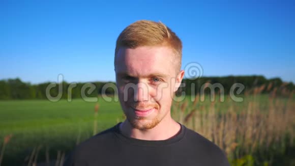 年轻微笑男子站在农村环境的肖像有胡子的帅哥用漂亮的相机视频的预览图