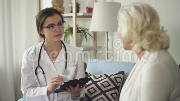 带着平板电脑的医生拜访了她家的高级妇女视频的预览图