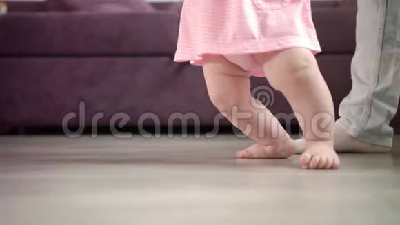 小女孩在她生命中迈出第一步幼儿学习行走小脚步视频的预览图