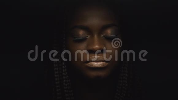 超现实特写肖像的年轻非裔美国女性模特与金色光泽的化妆面子艺术时尚概念视频的预览图
