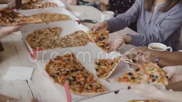 年轻的创意商业团队一起吃饭混合种族的人在现代办公室吃披萨享受食物视频的预览图