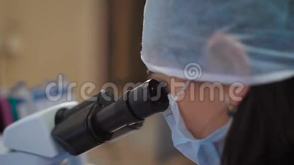 用显微镜封闭医用防护面罩和研究实验室工作帽的女科学家妇女视频的预览图