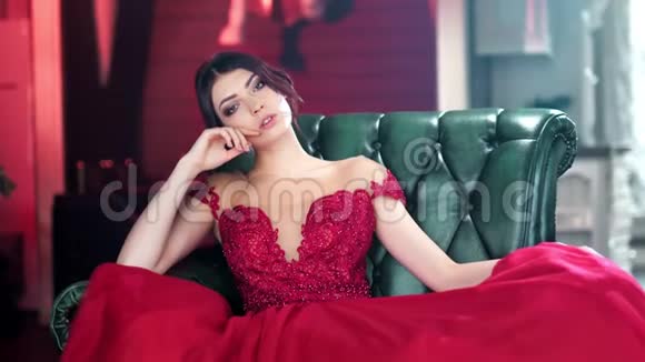 迷人的西班牙少女穿着红色晚礼服坐在老式扶手椅上中弹视频的预览图