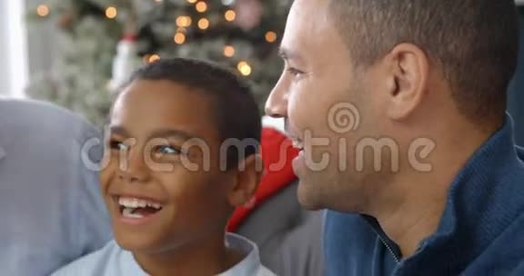圣诞节时男孩和父亲祖父坐在沙发上的慢动作顺序视频的预览图