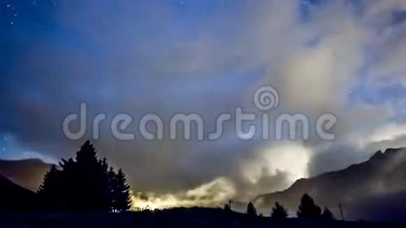 随着时间的推移夜空中的星星和月亮穿过带有山背景的快速云视频的预览图