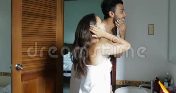浴室里的情侣女人洗脸在毛巾里和男人聊天做晨间例行公事视频的预览图