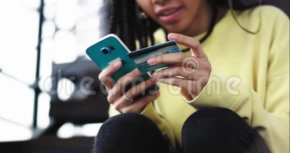 细节特写非洲女士用一张银行卡从她的智能手机上订购了一些东西她非常小心地键入她的银行视频的预览图
