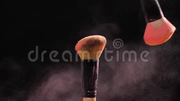 化妆品和美容的概念黑色背景上粉色粉末爆炸的化妆刷视频的预览图