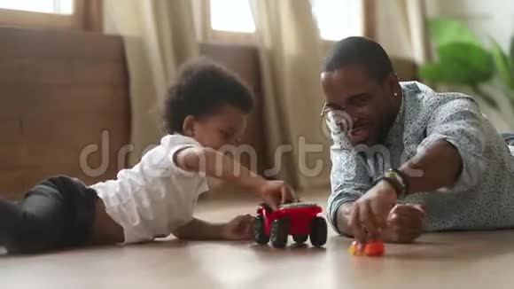 快乐的非洲可爱的小儿子玩玩具车爸爸视频的预览图
