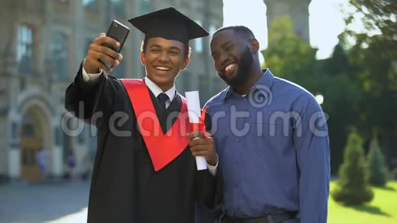 快乐大学生毕业披风和父亲自拍智能手机视频的预览图