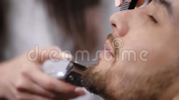 在时尚的理发店里一个留着胡须的年轻人正在理发女性手的形象视频的预览图