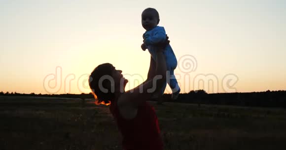 一个穿着紧身衣的中年女人在夕阳西下的田野里和孩子玩耍视频的预览图