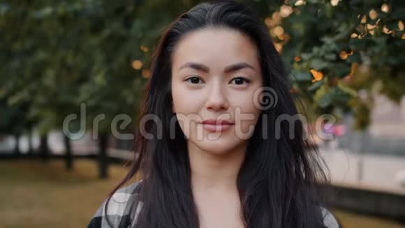 美丽的亚洲学生微笑独自站在城市公园的特写照片视频的预览图