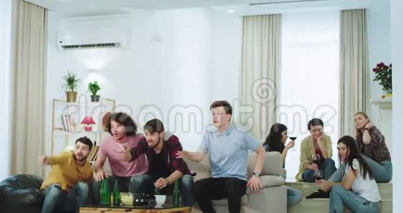 吸引人的多民族朋友男女在电视上观看他们庆祝胜利的足球赛视频的预览图