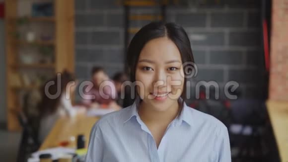 亚洲自信的女商人看着摄像机微笑着而她的多民族团队正在着手创业视频的预览图