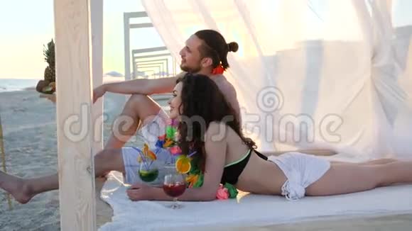 在异国的岛屿上为情侣们提供暑假背光年轻人穿着五颜六色的花环在平房里享受日光浴视频的预览图