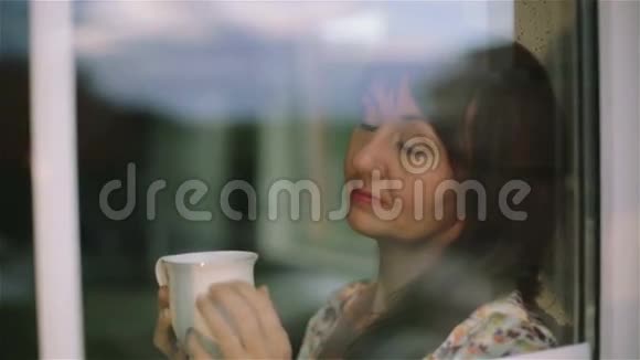 快关门体贴悲伤的黑发女人在外面喝着温暖的早茶和A梦视频的预览图