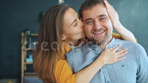 幸福的年轻女子亲吻和拥抱丈夫在家看镜头的肖像视频的预览图