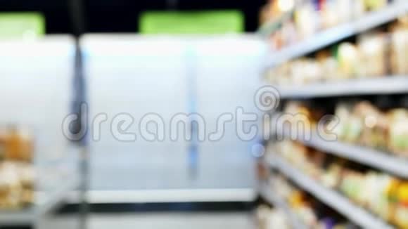 女人用绿色的购物车穿过商店在货架和超市之间视频的预览图