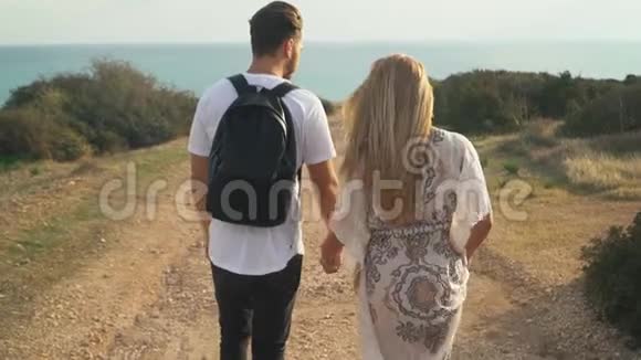 年轻漂亮的夫妇走在海边的沙路上手牵手视频的预览图