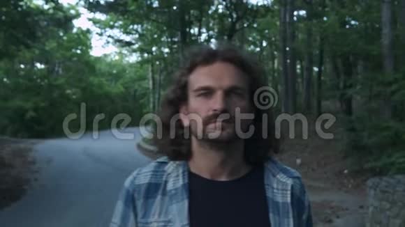 肖像一个年轻的嬉皮士在他的脖子上扔了一个长板他看着摄像机它位于森林里视频的预览图