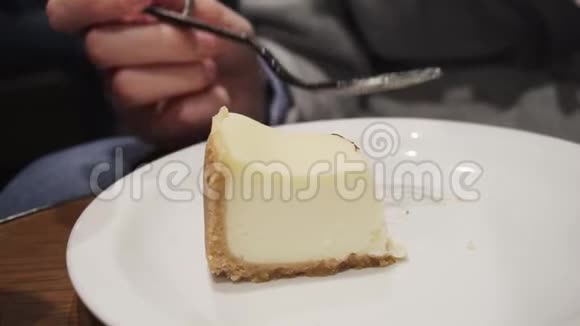 女孩吃新鲜奶酪蛋糕与叉子而坐在厨房或咖啡馆慢动作视频的预览图