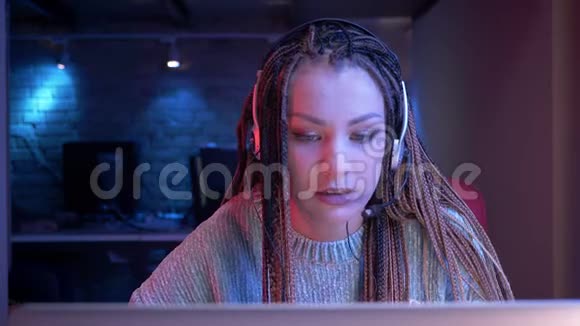 一位年轻有魅力的女性博客写手在耳机里播放视频游戏和现场直播视频的预览图