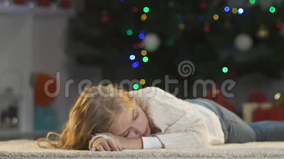 可爱的父母抚摸着睡在圣诞树旁的小女儿等待不了礼物视频的预览图