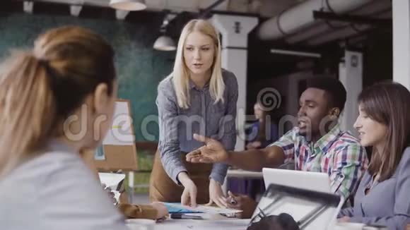 金发女队队长指导混合种族的年轻人现代办公室创意商务会议视频的预览图