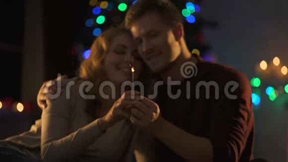 热情的情侣在圣诞装饰品附近亲吻手里拿着孟加拉灯视频的预览图