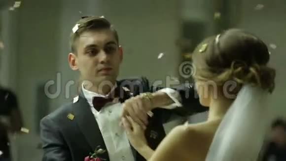 美丽的黑发新娘和英俊的新郎在被纸屑笼罩的婚礼晚会上跳舞非常招标视频的预览图