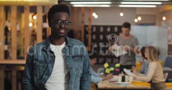 年轻的黑人微笑成功商人的肖像戴着时髦的眼镜站在现代办公室工作人员视频的预览图