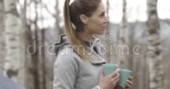 女人带着热饮料咖啡或茶给露营的男人情侣恋爱秋季户外旅行视频的预览图