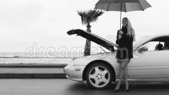 一个女人站在伞下靠近破车的黑白镜头视频的预览图
