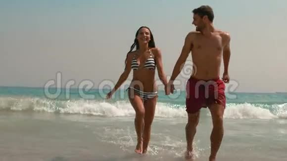 一对幸福的夫妇手牵着手从水里跑出来视频的预览图
