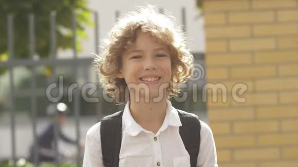 一个漂亮的迷人的高加索卷发男孩的特写照片学童面带微笑视频的预览图